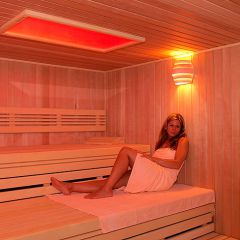 Wellness - Frau sitzt mit Handtuch in der Sauna